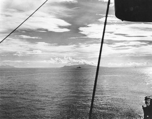 Figure 4: A U.S. destroyer steams up what later became known as "Iron Bottom Sound", the body of water between Guadalcanal and Tulagi, during landings on both islands, 7 August 1942. Savo Island is in the center distance and Cape Esperance, on Guadalcanal, is at the left. Photographed from USS San Juan (CL-54) from a location approximately due east from the northern tip of Savo Island. (National Archives, 80-G-13539)