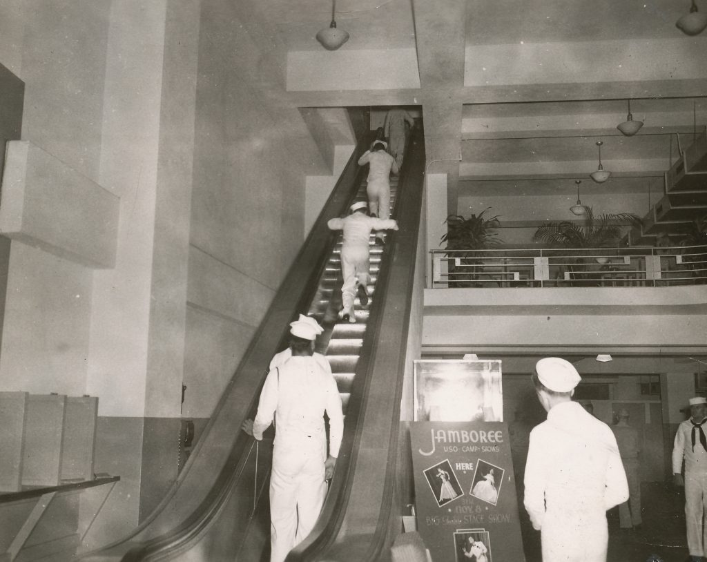 Sailors on the escalator in the lobby of the USO Victory Club.